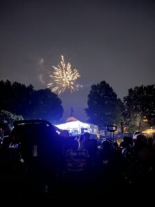 bright yellow firework over a dark sky, above a blue lit stage